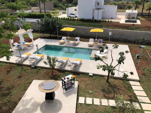 斯佩基亚B&B Casa Karina Pool&Rooms的享有带椅子和桌子的游泳池的上方景色