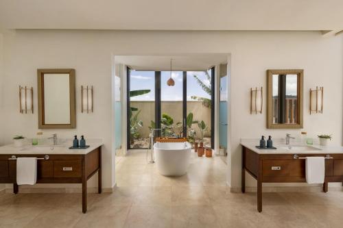 Six Senses La Sagesse的浴室配有两个盥洗盆和浴缸。