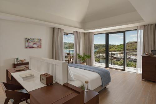 Six Senses La Sagesse的酒店客房配有一张床、一张书桌和窗户。