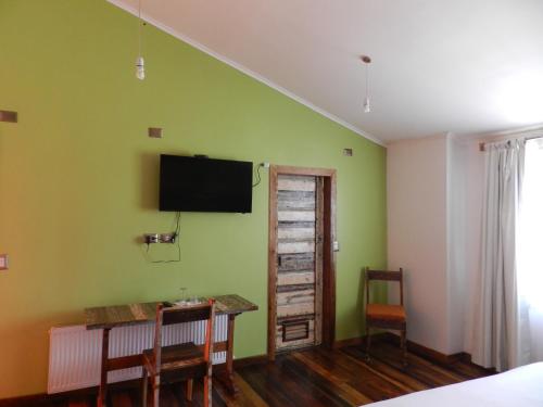 瓦尔迪维亚绿香酒店的一间卧室设有绿色的墙壁、书桌和电视。