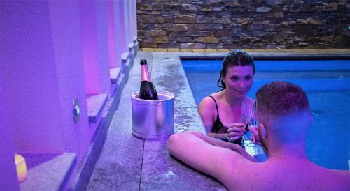 佩尔吉内瓦尔苏加纳米拉啦古公寓酒店的游泳池里的男人和女人,喝一瓶葡萄酒