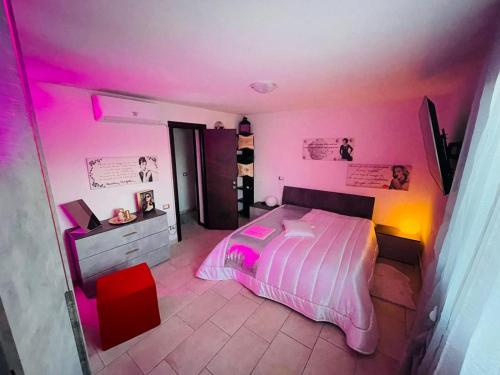Appartamento a Udine con doccia idromassaggio的卧室配有粉红色的灯光和一张床
