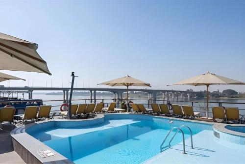 阿斯旺NILE CRUISE NCA every Saturday from LUXOR 4nights & every Wednesday from ASWAN 3 nights的船上的游泳池,配有椅子和遮阳伞