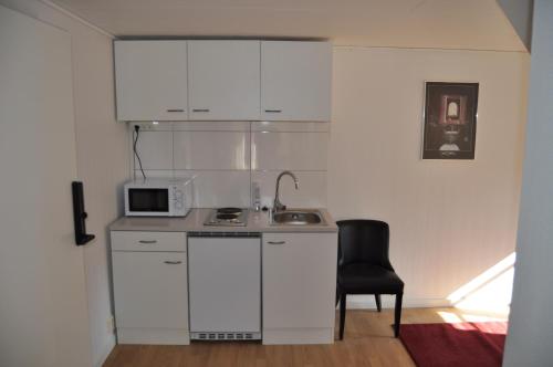 långstorp的厨房配有白色橱柜、微波炉和椅子