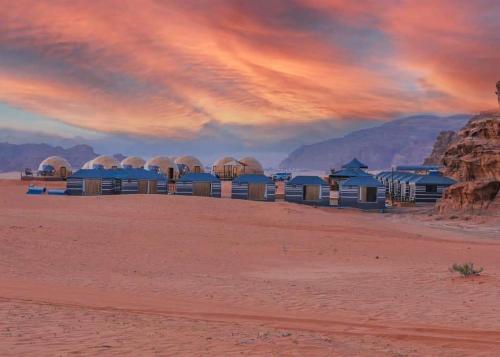 瓦迪拉姆Taj Wadi Rum camp的日落时分在沙漠中的小屋