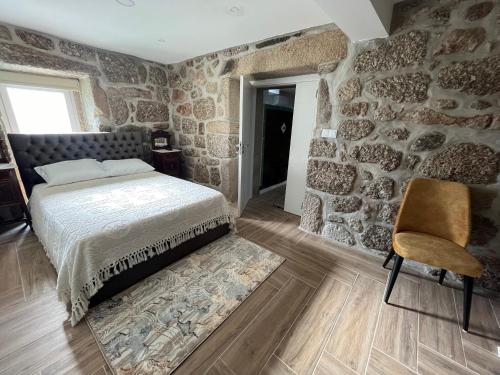 FarminhãoCasa do Compasso的一间卧室设有石墙、一张床和一把椅子