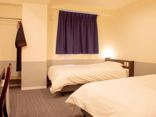 松山Hotel Taiyo Noen Nibancho的酒店客房设有两张床和窗户。