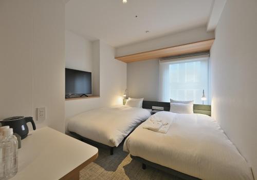 大阪Prince Smart Inn Osaka Yodoyabashi的一间酒店客房,设有两张床和电视