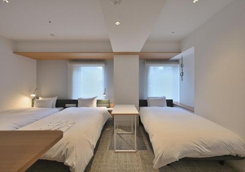 大阪Prince Smart Inn Osaka Yodoyabashi的带2扇窗户的客房内的2张床