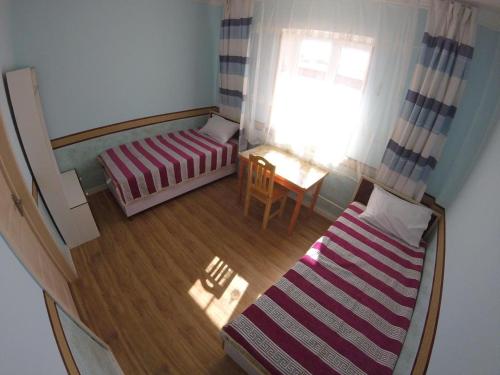 乌兰巴托Good Karma Hostel的小房间设有床、桌子和窗户