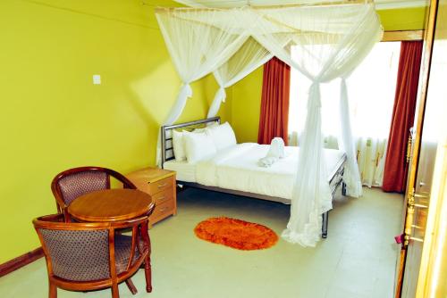埃尔多雷特Wagon Wheel Hotel Eldoret的卧室配有1张床和1张桌子及椅子