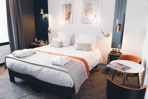 昂热Hôtel D'Anjou的酒店客房设有两张床和一张桌子。