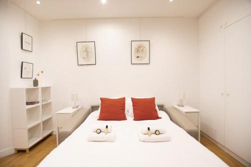 巴黎GuestReady - Charming Studio – 5 mins to Pantheon的白色卧室配有带橙色枕头的大型白色床