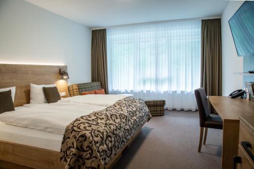 布莱特瑙Hotel Hofgut Sternen的酒店客房设有一张大床和一张书桌。