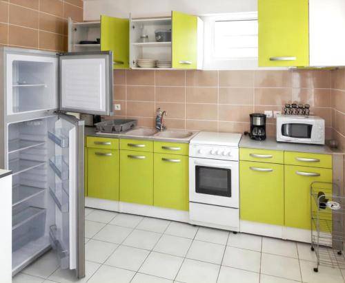 DucosAppartement de 2 chambres avec jardin clos et wifi a Ducos的厨房配有黄色和绿色的橱柜和冰箱。