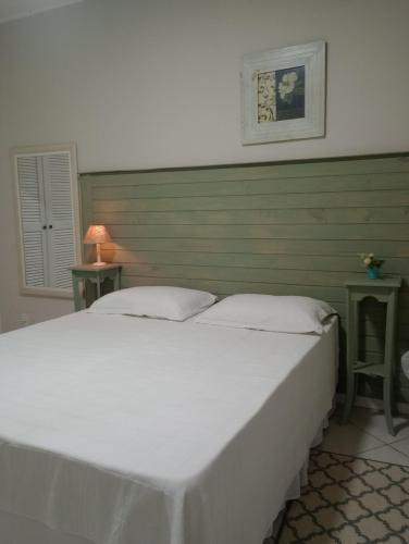 康赛瓦托利亚Pousada das Flores的一张大白色的床,位于带两张桌子的房间