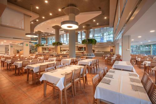萨洛Ponient Dorada Palace by PortAventura World的一间设有白色桌椅的用餐室