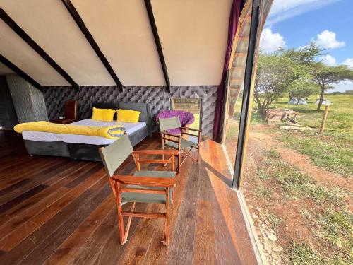 Oloitokitok Kilimanjaro view cabin-Amboseli的狩猎帐篷内带一张床和椅子的房间