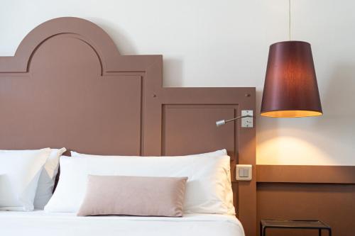 圣马洛拉迈松德斯阿玛托斯酒店的一间卧室配有一张带大床头板和灯的床
