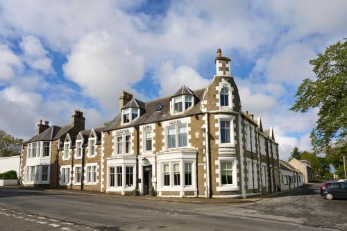 HalkirkUlbster Arms Hotel near Thurso的街道上一座带白色窗户的大型砖砌建筑