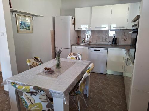 卡尔卢巴格Villa Vesna, 70m from beach的一间厨房,配有白色家电和桌椅