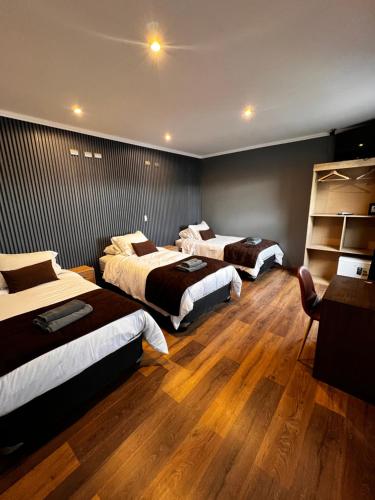 奥索尔诺Hotel Mackenna的酒店客房,设有三张床,铺有木地板