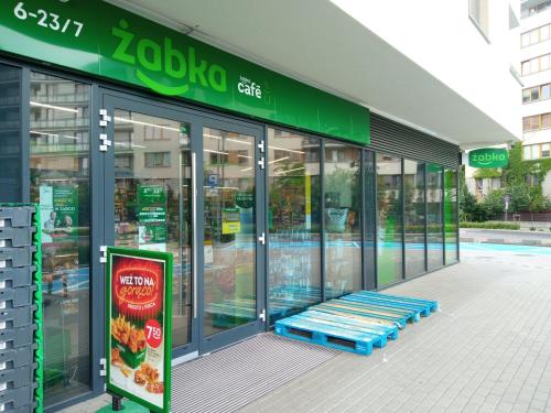华沙Apartamenty Bokserska的前面的商店外面有蓝色的长凳