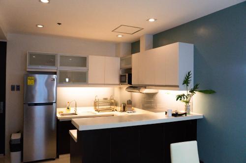 马尼拉The Pearl - BGC Blue Sapphire 1BR的厨房配有白色橱柜和不锈钢冰箱