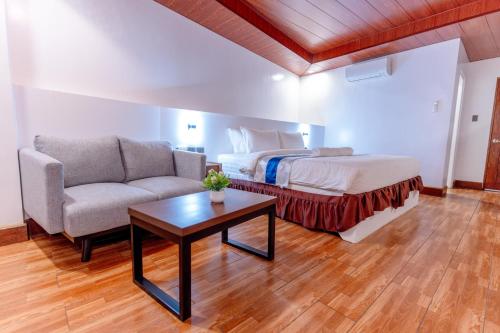 SantiagoSantiago Cove Hotel and Restaurant的一间卧室配有一张床、一张沙发和一张桌子