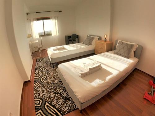 琳达阿韦立亚Lisbon T2 apartment in condominium in Linda-a-Velha Oeiras Lisbon的一间带两张床的卧室和地毯