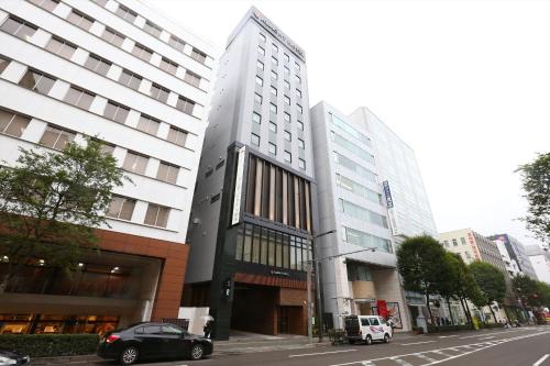 仙台仙台阿尔蒙特酒店的一条城市街道上的建筑,前面有汽车停放