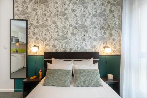 南希Nemea Appart Hotel Home Suite Nancy Centre的一张带两个枕头的床和一面带镜子的墙壁