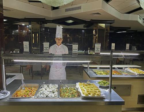 突尼斯hôtel Diplomat的厨师站在厨房的柜台后面,提供食物