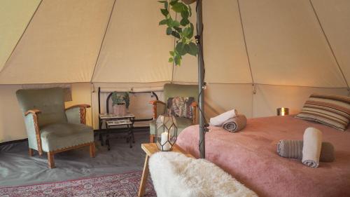 Nederweert-EindBell Tent in een Voedselbos的帐篷内的卧室,配有一张床和椅子