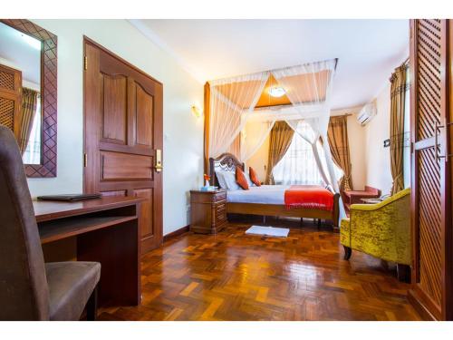 基苏木Wigot Gardens Hotel的一间卧室配有一张带书桌的床和窗户。