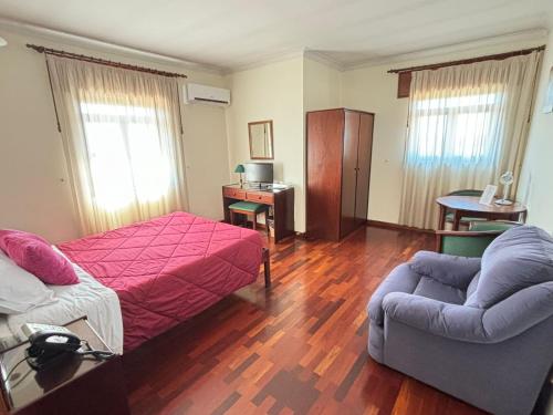 莫加多鲁Hotel Trindade Coelho的一间卧室配有一张床、一张沙发和一把椅子