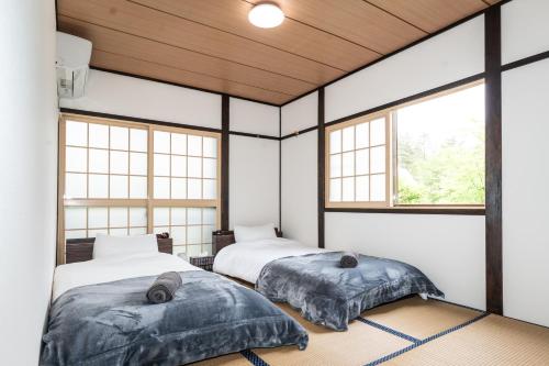 白马村Ringo Cottage的带窗户的客房内的两张床
