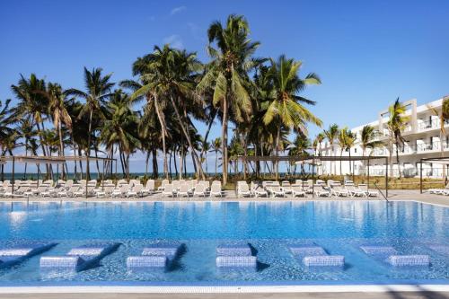 勒莫尔尼Riu Turquoise - All Inclusive的一个带躺椅的游泳池,棕榈树