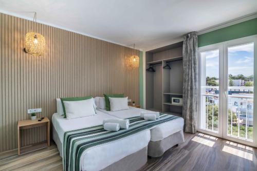 卡拉达沃MarSenses Natura Olea Hotel的一间卧室设有两张床和大窗户