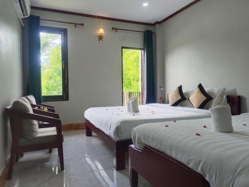 万荣Dokchampa Hotel的一间卧室配有两张床、椅子和两个窗户。