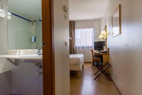 阿尔卡拉德荷那利斯Travelodge Madrid Alcalá de Henares的一间带水槽的浴室、一张床和一张书桌