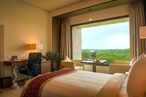 艾哈迈达巴德Narayani Heights, Ahmedabad的配有一张床、一张书桌和一扇窗户的酒店客房