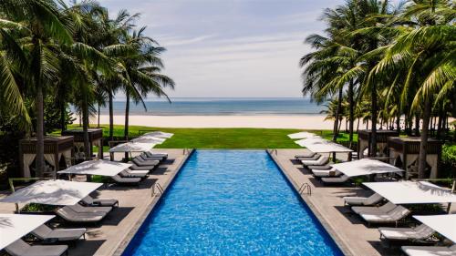 会安Shilla Monogram Quangnam Danang的一个带躺椅的游泳池和海滩