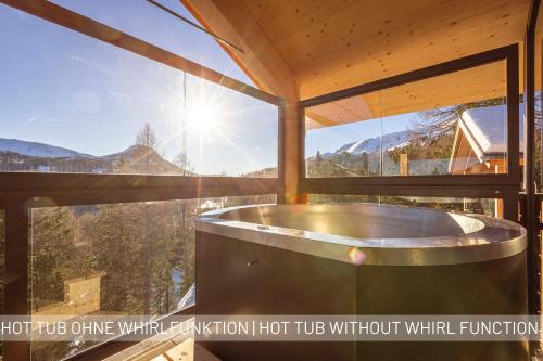 图拉彻霍赫Naturchalets Turracher Höhe by ALPS RESORTS的带大窗户的客房内的热水浴池