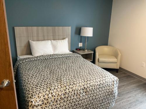 温斯顿·塞勒姆WoodSpring Suites Winston-Salem near Hanes Mall的一间卧室配有一张床、一把椅子和一盏灯