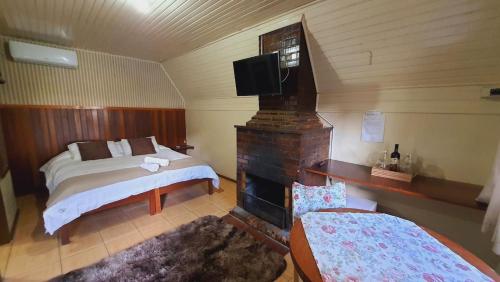 格拉玛多Villa Chalés Gramado - OH HOTÉIS的一间卧室配有一张床、一个壁炉和一台电视。