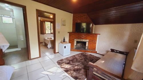 格拉玛多Villa Chalés Gramado - OH HOTÉIS的客厅设有壁炉和电视。