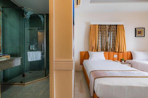 胡志明市Fortune 1127 - Central Hotel的一间卧室设有两张床和玻璃淋浴间