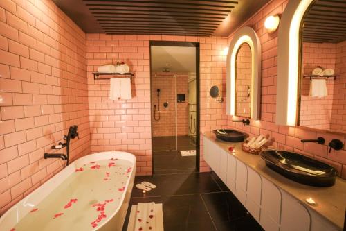 KondottiPushpak Grande的粉红色的浴室设有两个盥洗盆和一个浴缸