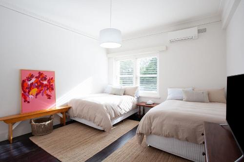 悉尼A touch of Pink, Bellevue Hill IH的白色的客房设有两张床和窗户。
